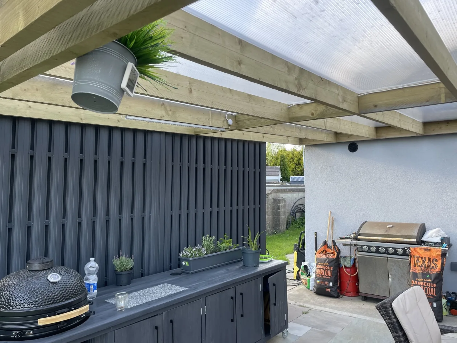 Outdoor kitchen with steel slat walls and timber pergola