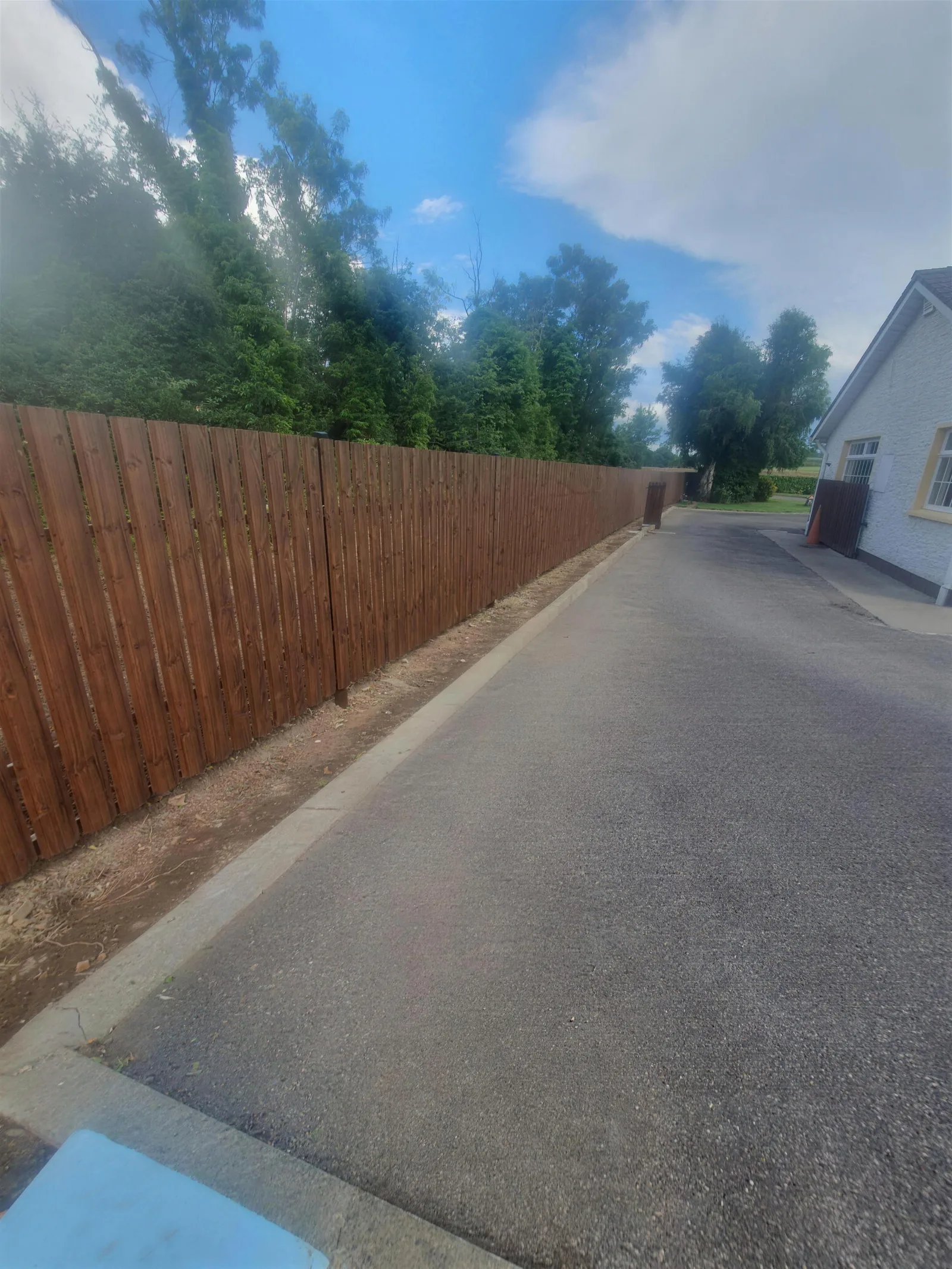 Brown vertical board fence along a driveway