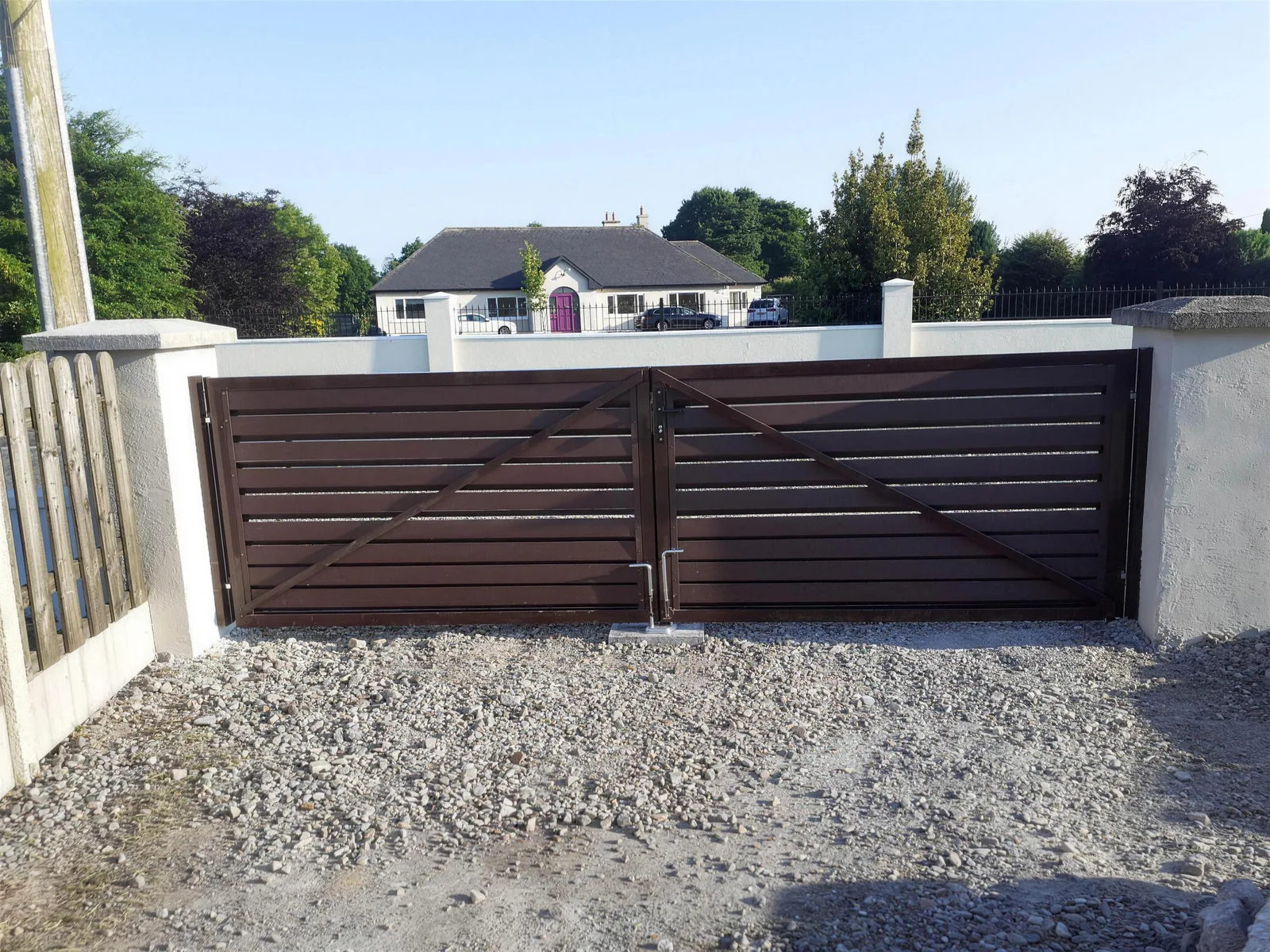 Chocolate brown horizontal board double gates between rendered pillars